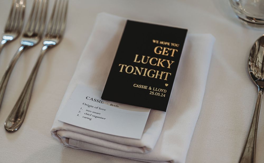 Wedding place setting with 'Get Lucky Tonight' card on folded white napkin.