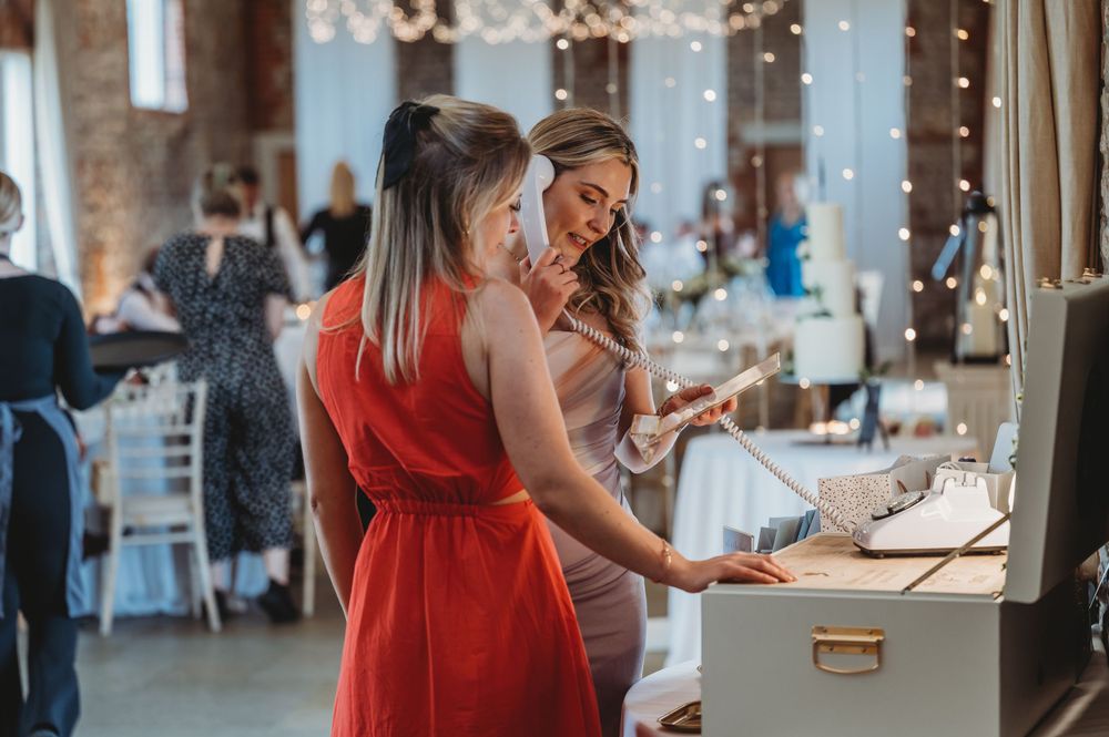 Two guests in formal attire browse wedding guest book at reception.