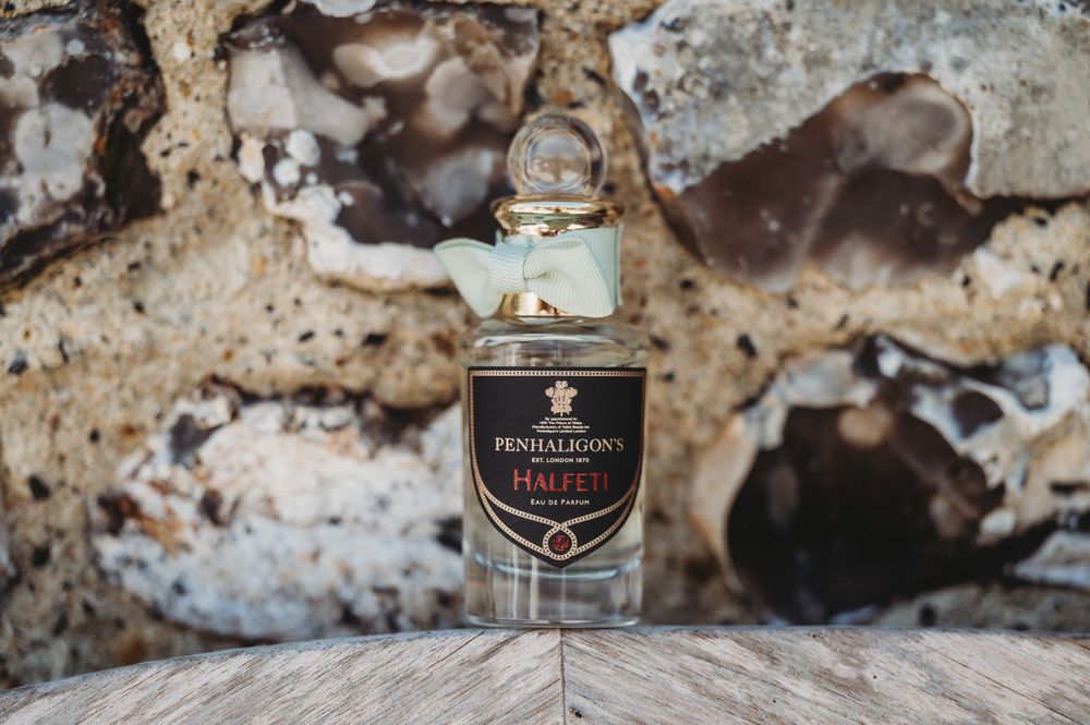 Glass bottle of Hendricks gin positioned on rustic wooden surface against stone wall.
