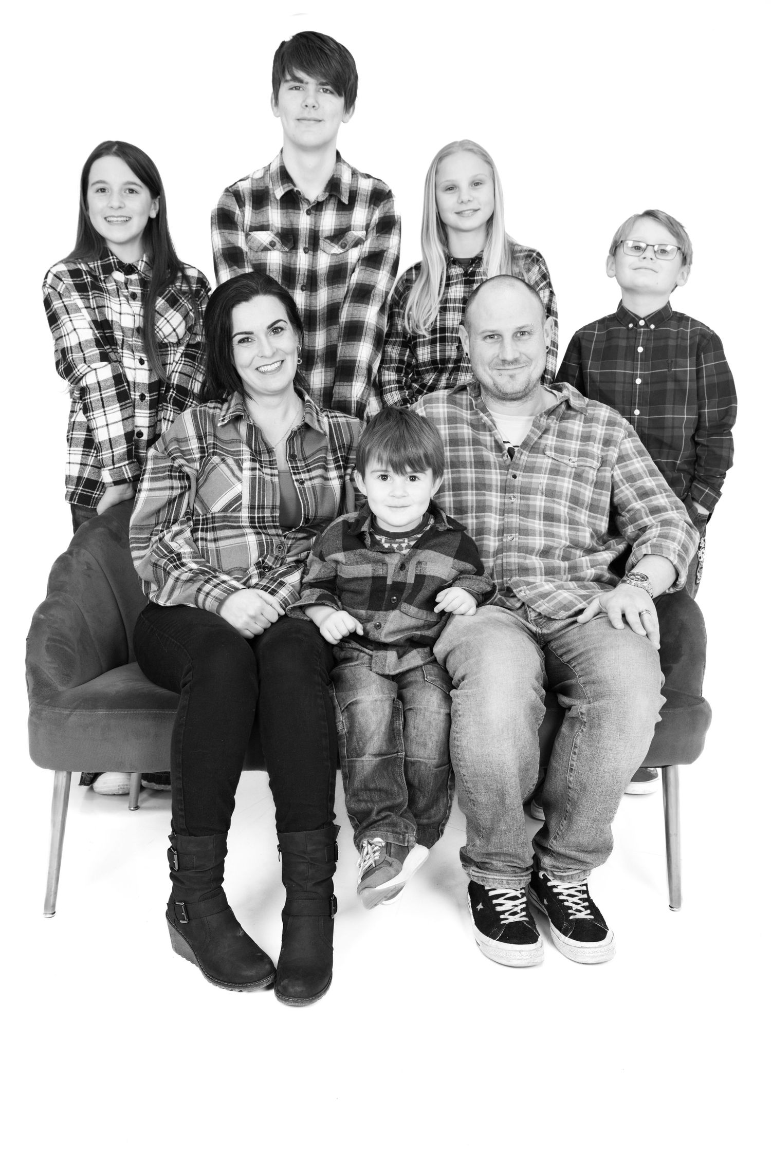 Black and white portrait of group wearing plaid shirts sitting together in informal studio setting.