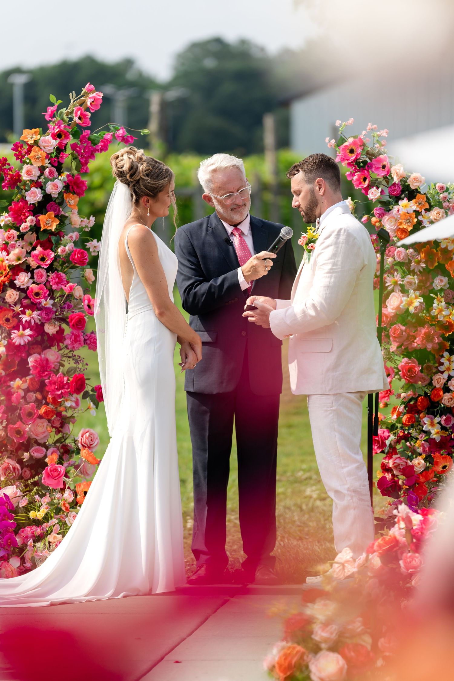 Wedding ceremony under a stunning floral arch with pink and orange blooms.