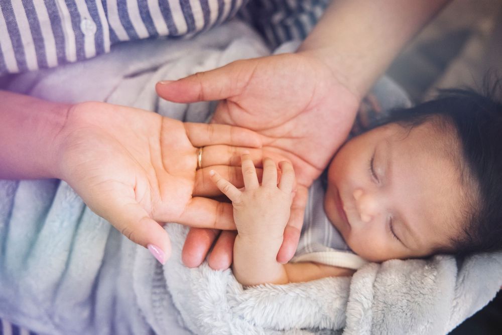 Close-up shot of baby's feet being gently massaged by adult hands with cream or lotion.