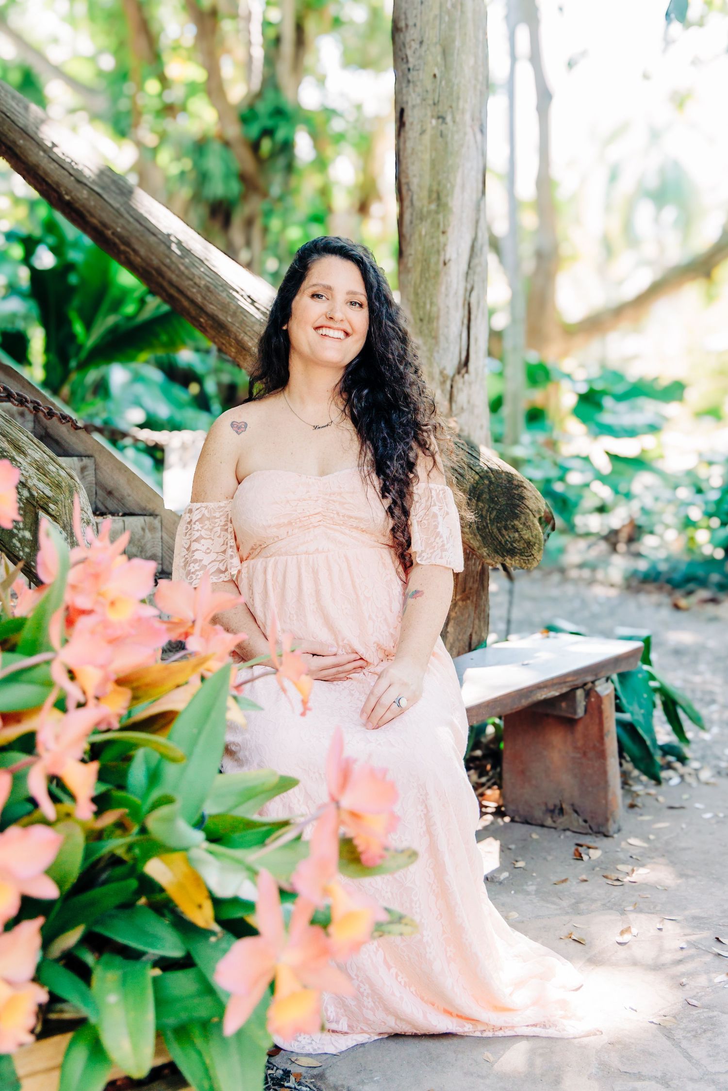 Maternity photographer Palm Beach County portrait of an expecting mother surrounded by tropical greenery and pink flowers.