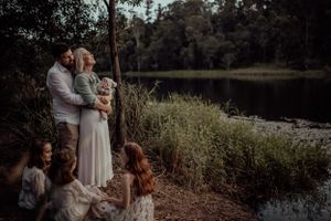 A romantic evening photo of a couple sharing an intimate moment by a serene lake surrounded by nature.