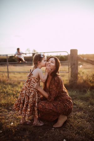 A touching moment between two people in a floral dress against a rustic wooden fence at sunset.