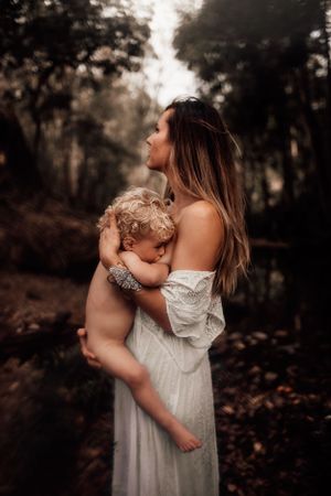 Ethereal portrait in white dress against moody forest backdrop during sunset.