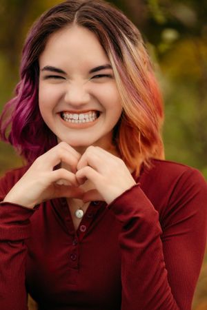 Highschool senior portrait of a girl with vivid hair colors making a heart with her hands