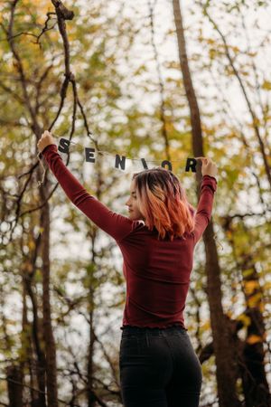 Minnesota Graduating high schooler holding letters spelling "senior" with a fall backdrop