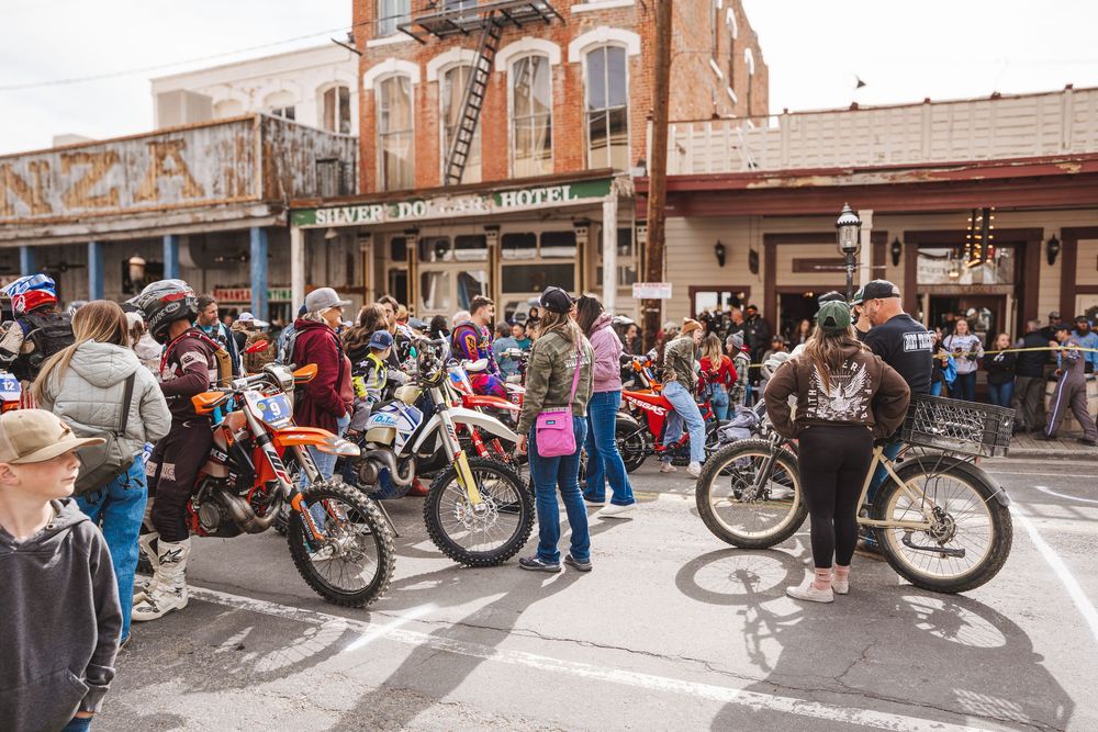 Crowd of motorcyclists and dirt bikes gathered on a busy street during an outdoor motorcycle rally event.