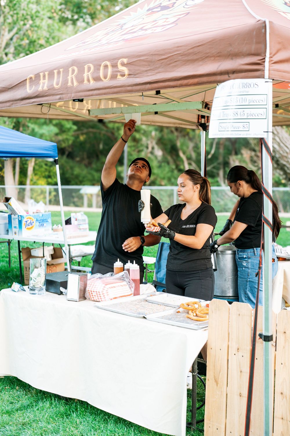 Food vendors serve from white tents at outdoor festival on green lawn.