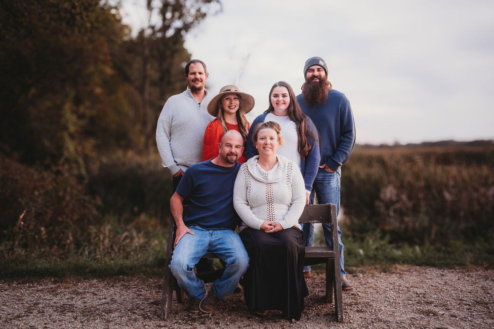 Family group poses for casual outdoor portrait on rocky terrain during overcast day.