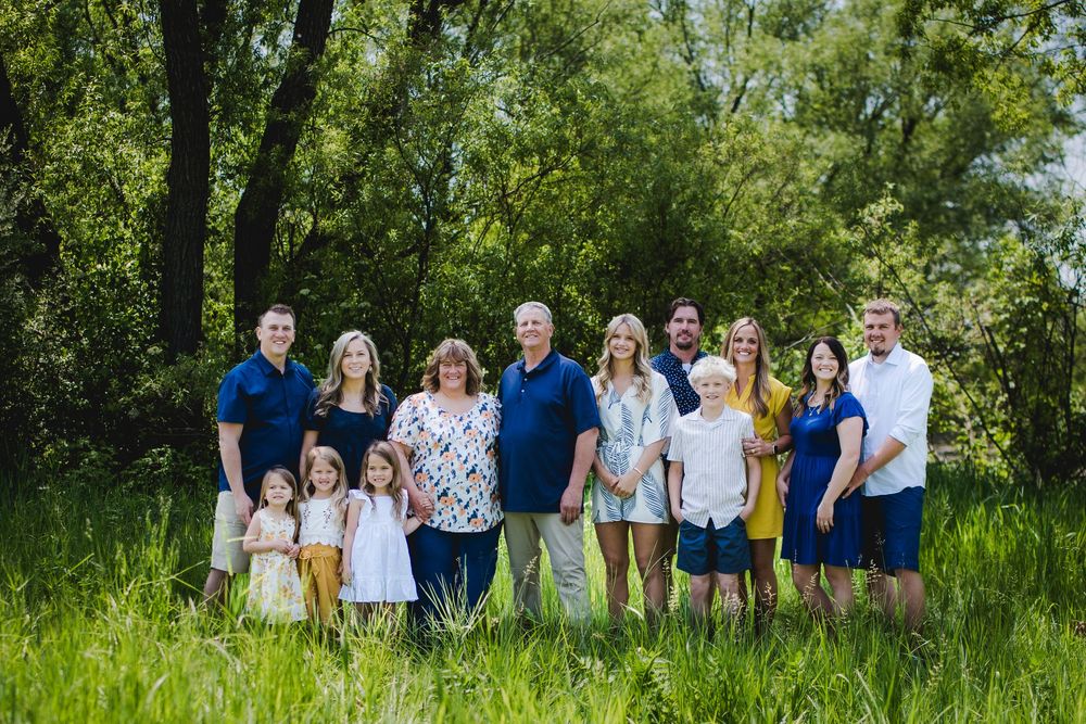 Group of people wearing coordinated blue and white outfits pose together in a lush green outdoor setting.