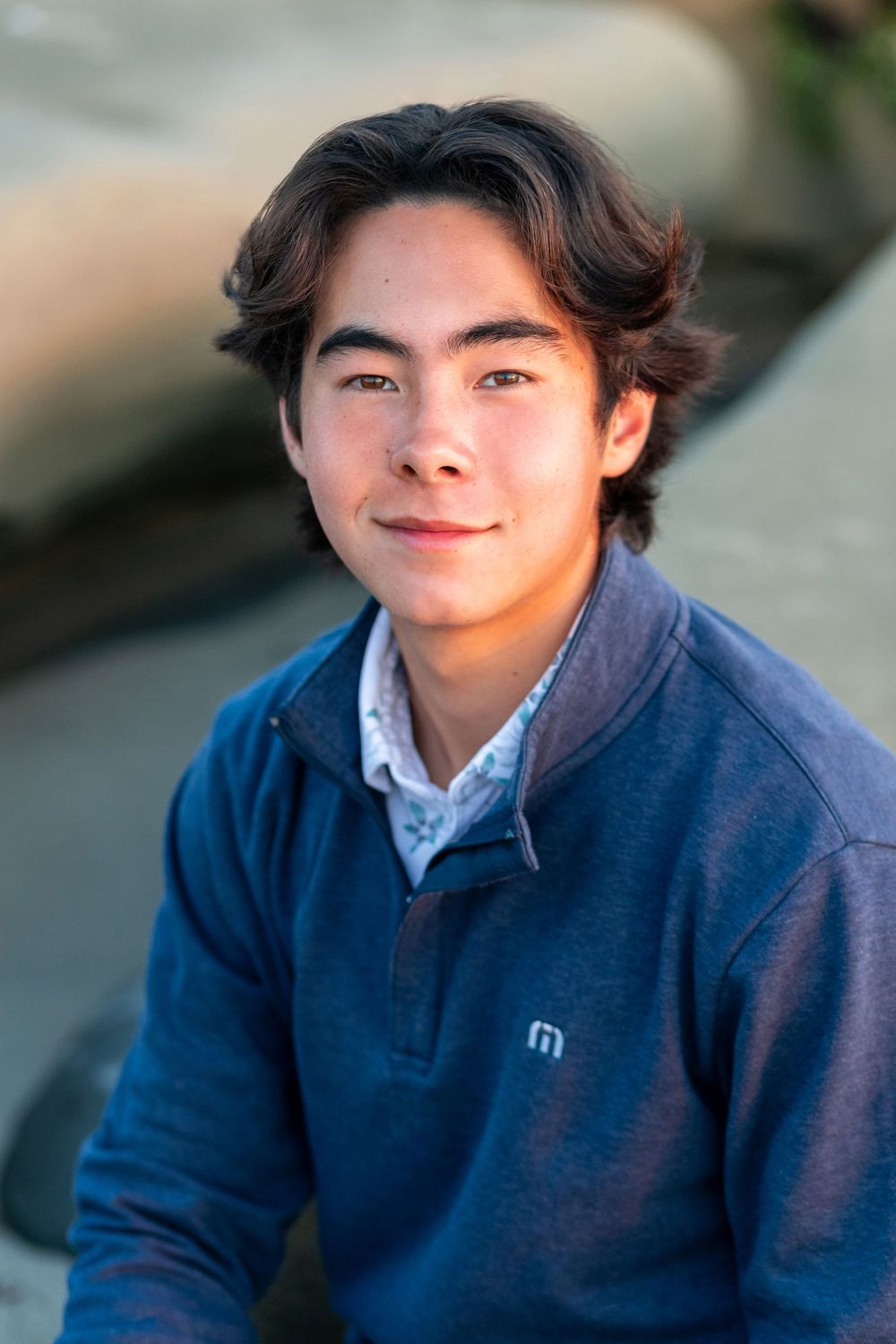 A person wearing a navy blue sweater smiles warmly in a series of casual outdoor portrait shots.