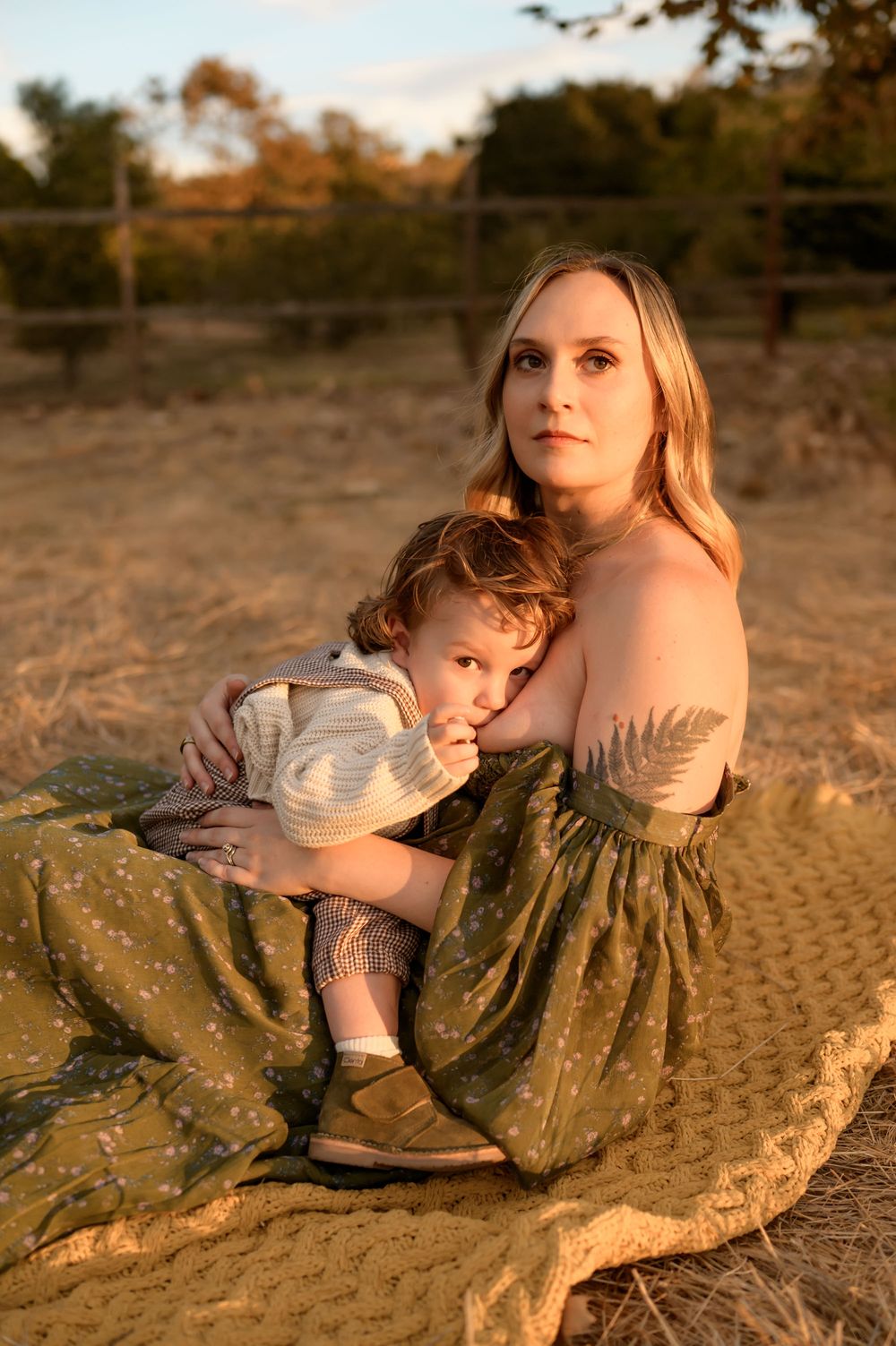 Breastfeeding mommy and me photoshoot in Santa Barbara of woman sitting in golden field at sunset by Ventura photographer