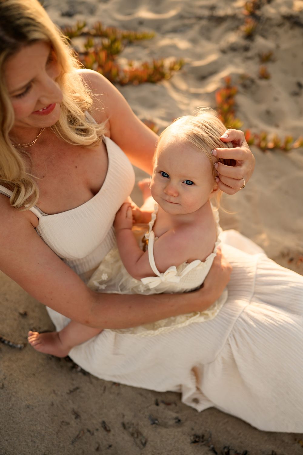 mommy and me photoshoot at Ventura beach on grassy sand dunes of mom sitting on sand with baby girl, by Santa Barbara photographer
