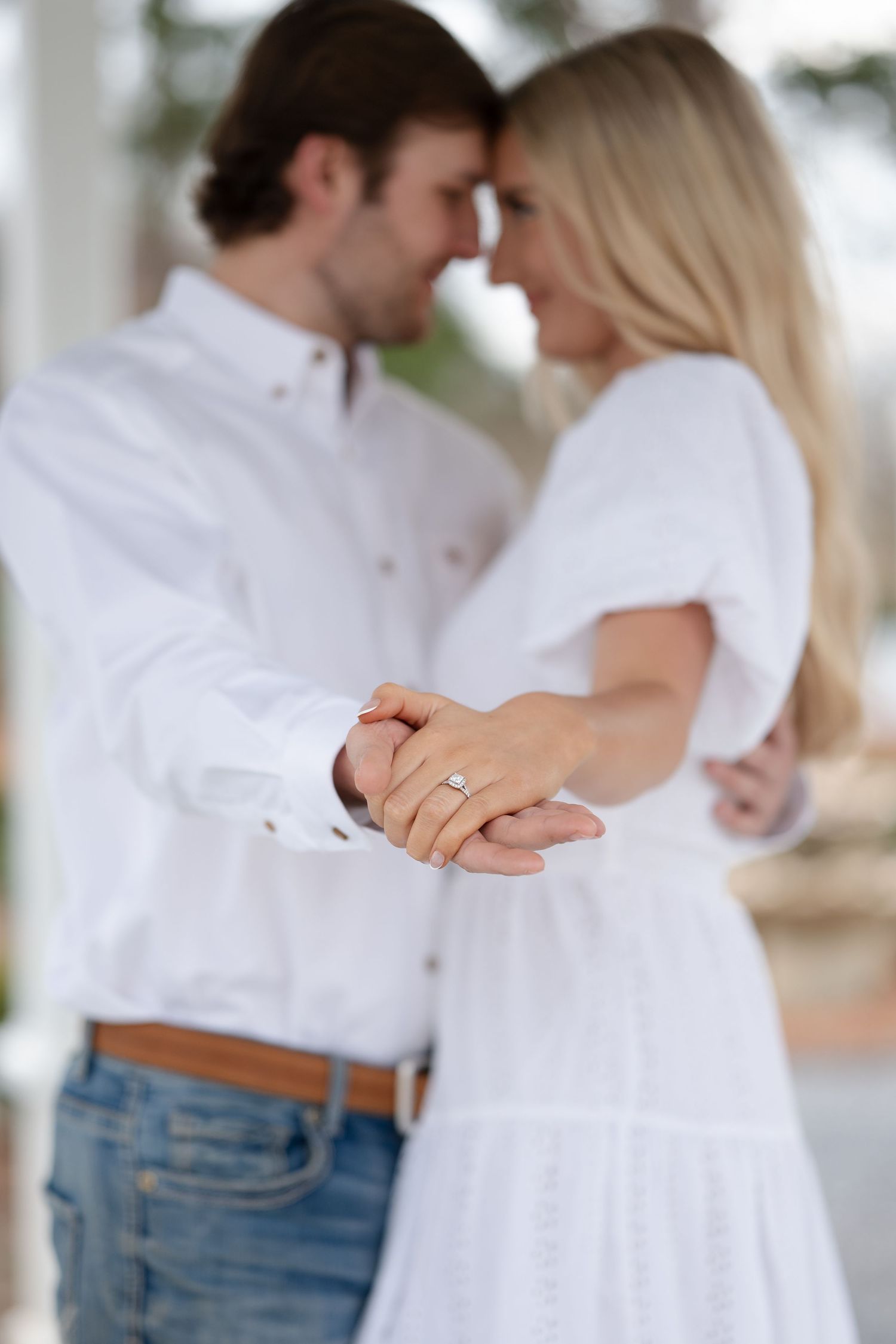 A romantic couple in white shirts and jeans embrace and hold hands in a series of intimate poses.