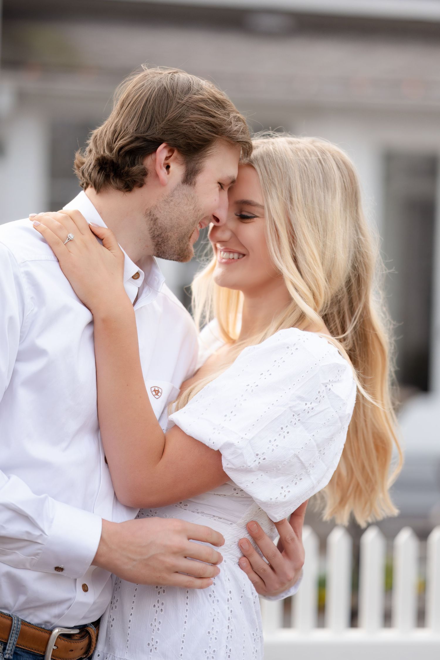 A romantic couple in white outfits embrace and smile together in a series of candid outdoor photos.
