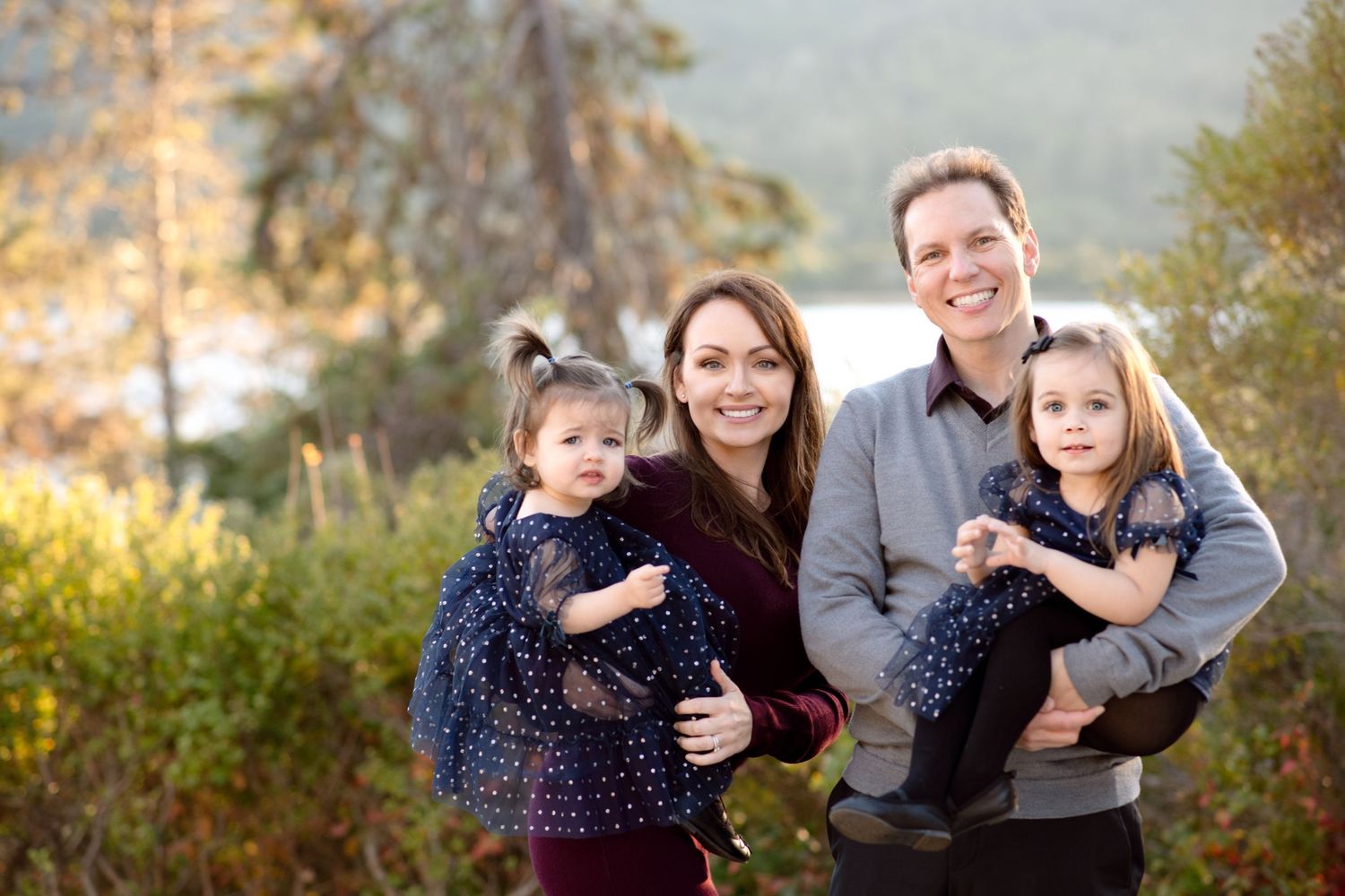 Family portrait outdoors with scenic mountain backdrop at sunset.
