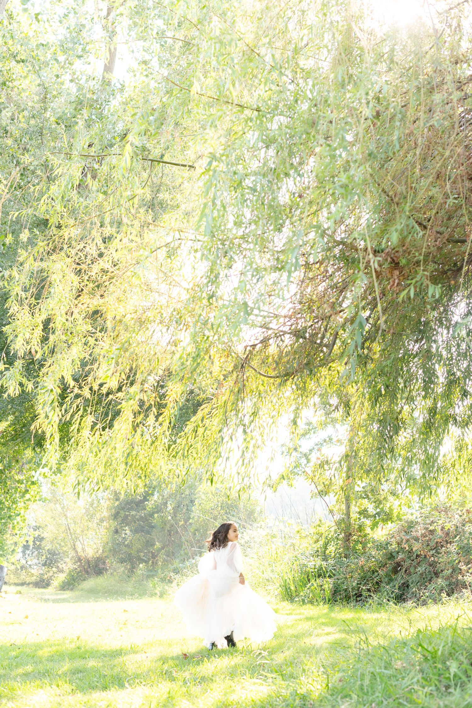 Ethereal bridal portrait under weeping willow trees with dreamy natural lighting.