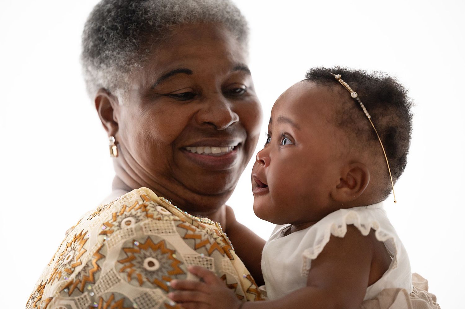 Heartwarming moment between elder and baby against white backdrop.