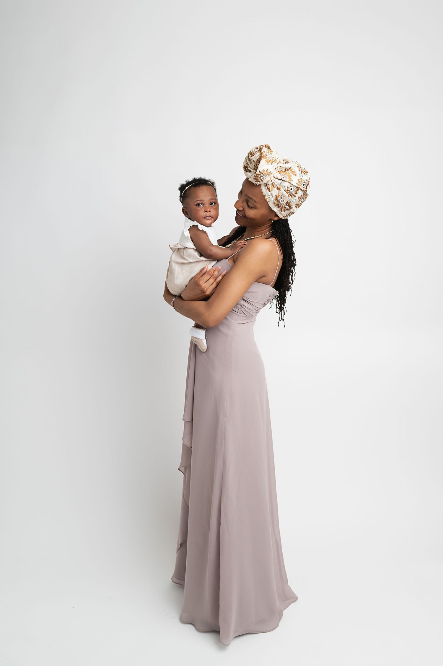 A tender moment between parent and child in elegant gray dress against white backdrop.