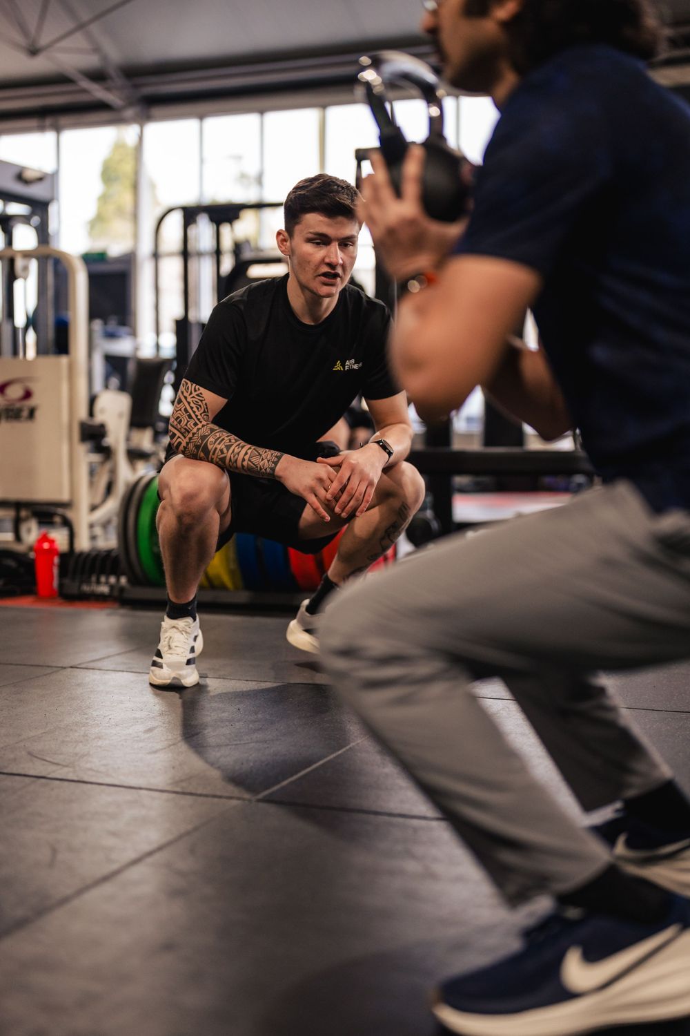 Personal trainer guiding a client through a squat at Freedom Gym in Tortworth.
