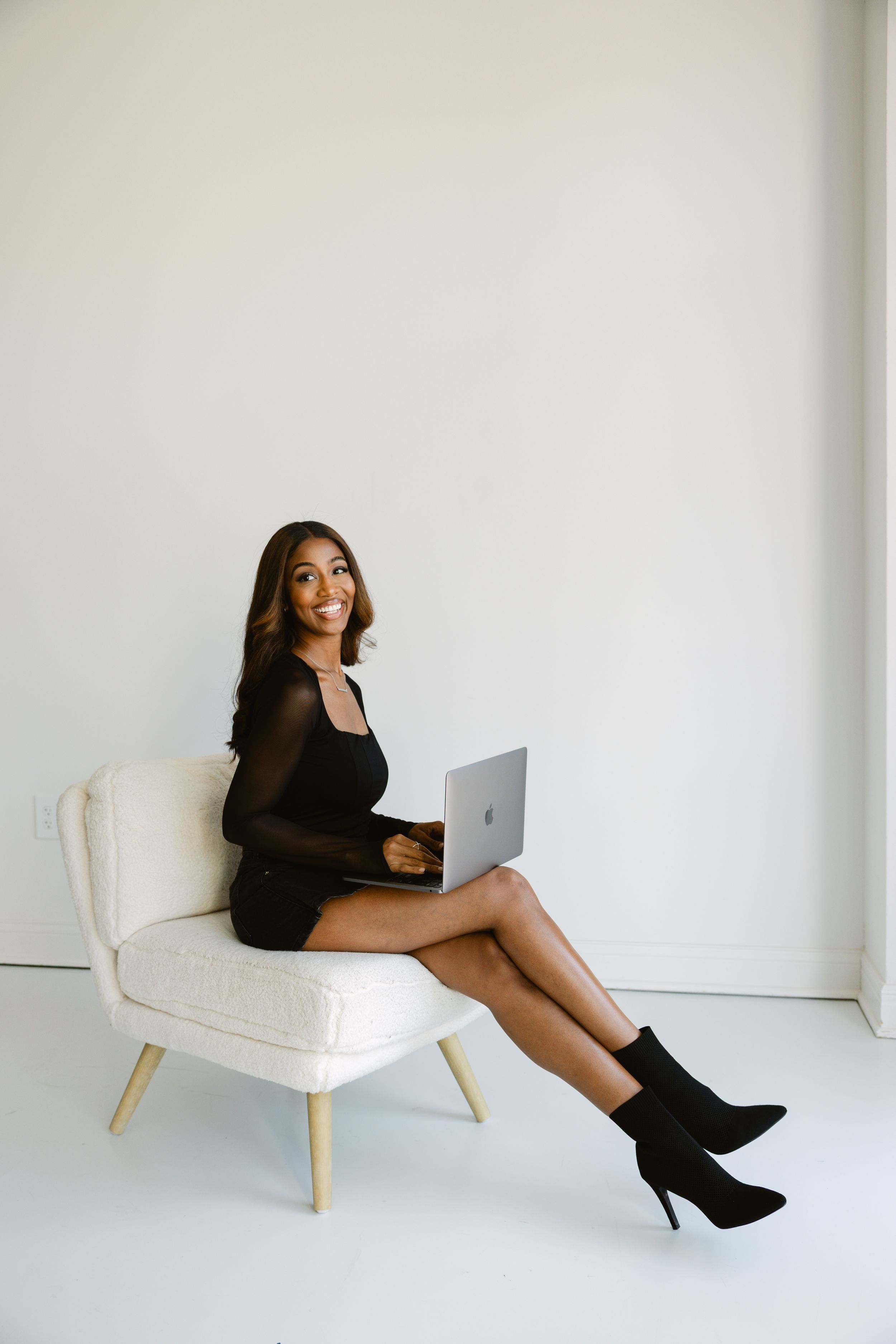 A photographer sitting in chair holding laptop during a branding session at a natural light studio.