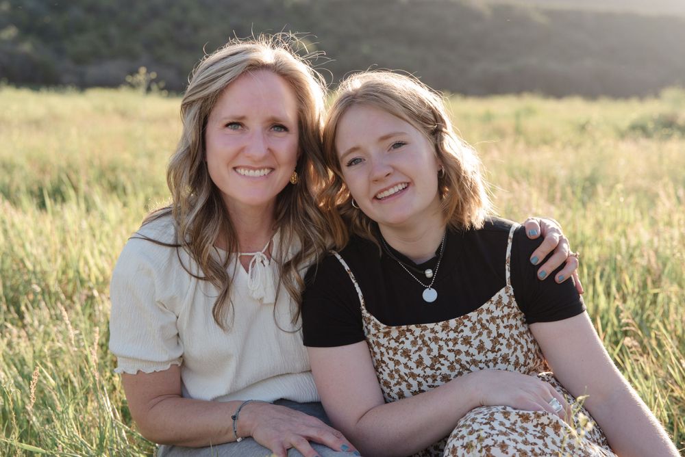 Two people sitting together and smiling in a golden field at sunset.