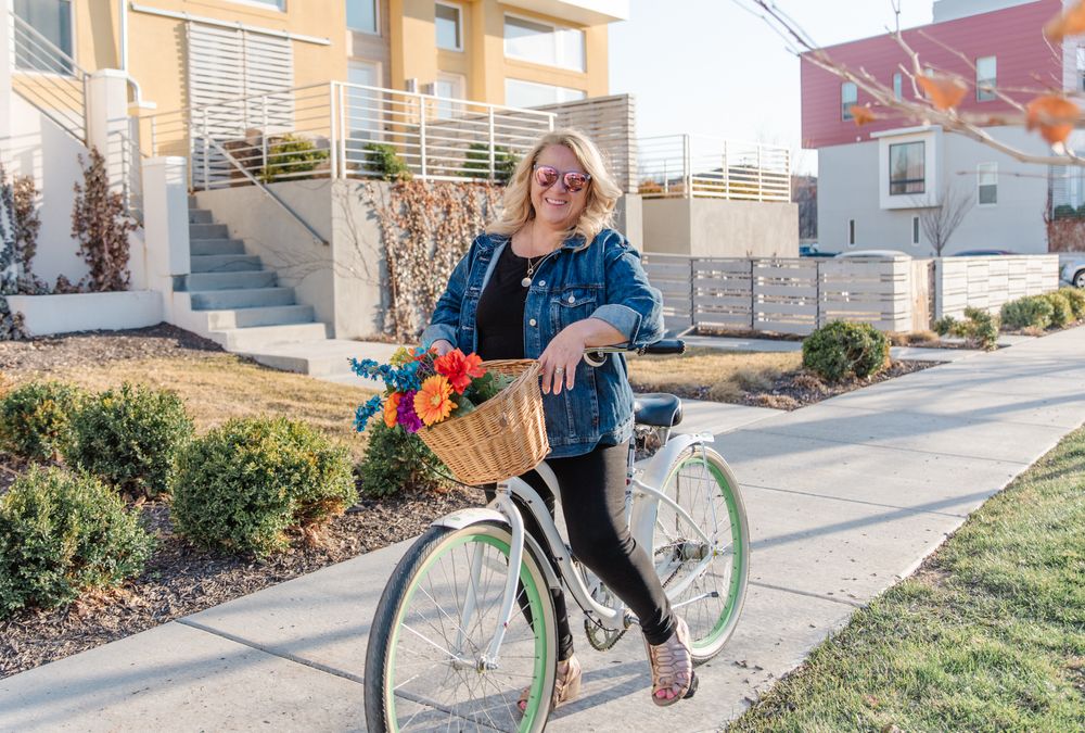 Person riding mint green bicycle with basket along suburban street.