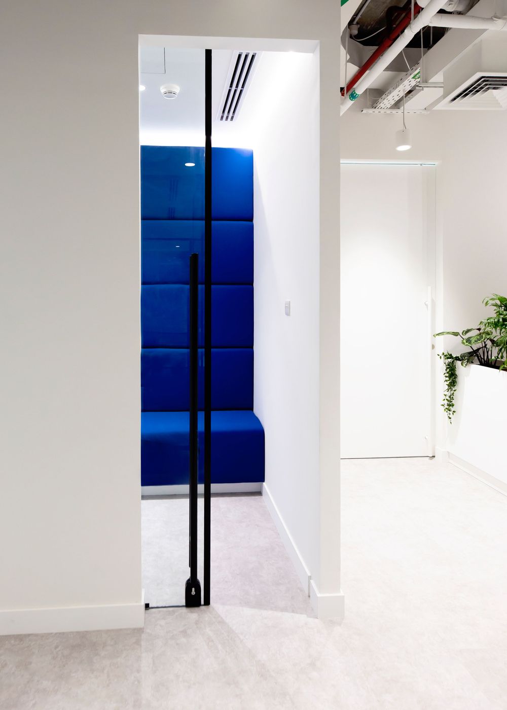 Modern corridor with bright blue upholstered bench and minimalist design.