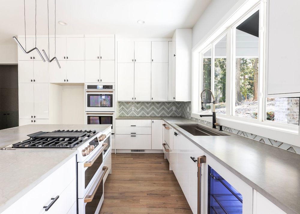 Modern white kitchen with marble countertops, stainless appliances and abundant natural light.
