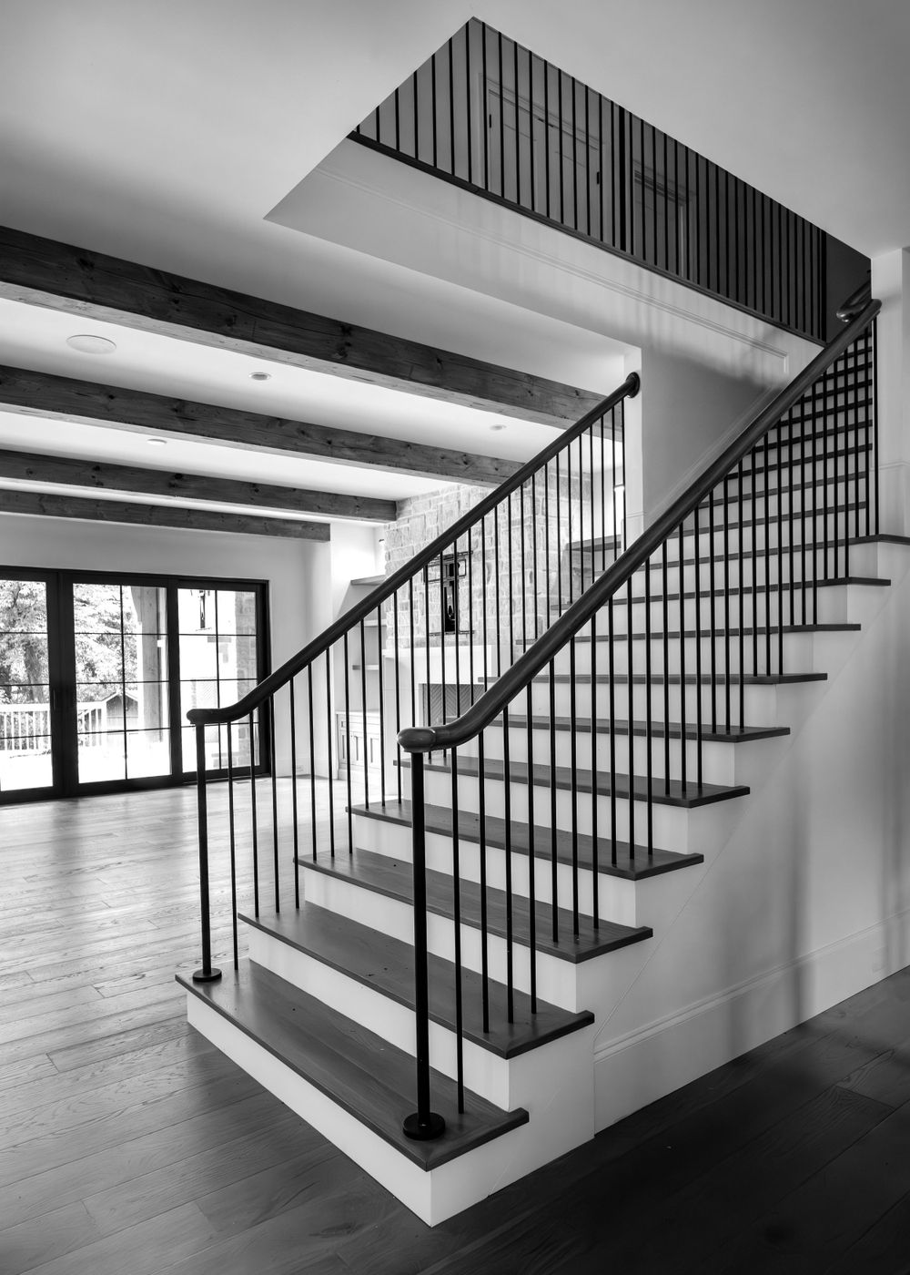 Elegant black and white staircase with iron railings and wooden steps in a modern home.
