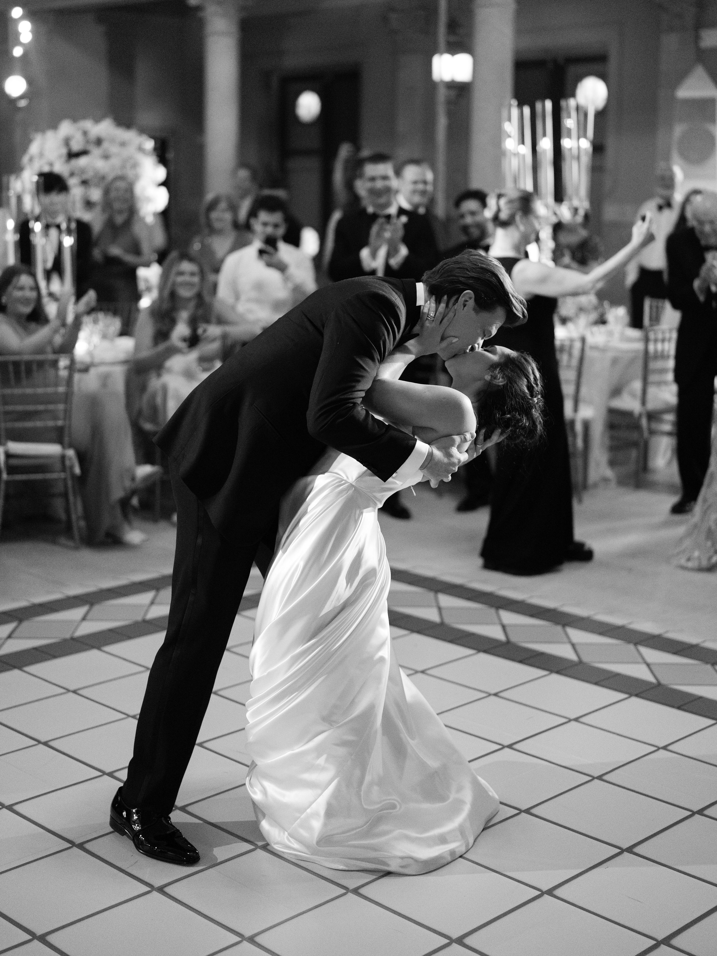 Black and white photograph of wedding dance moves on a tiled ballroom floor.