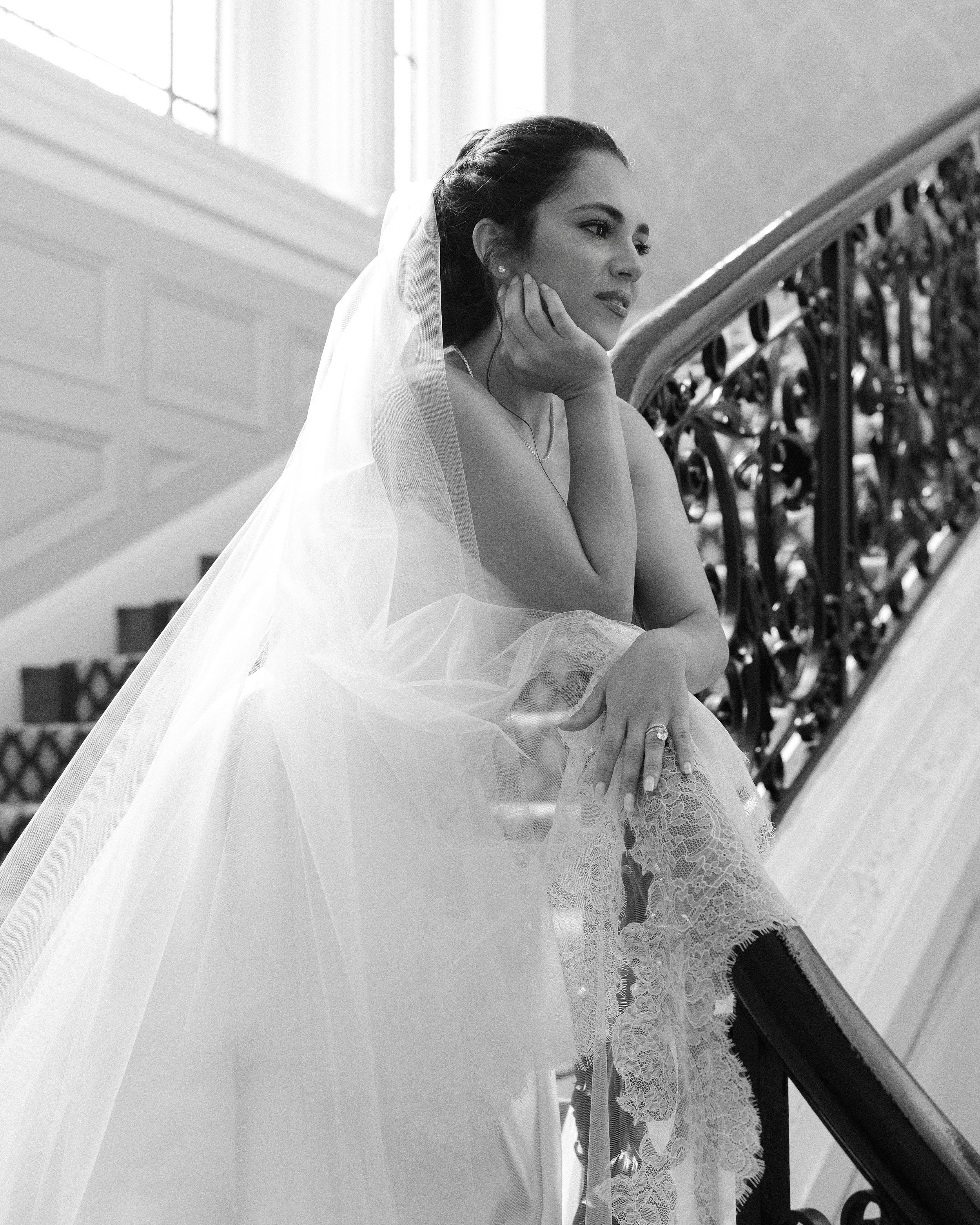 Side view of flowing white wedding gown near ornate staircase railing.