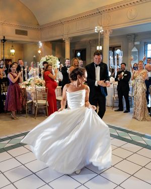 A bride twirls her wedding dress on a black and white checkered dance floor during the reception.