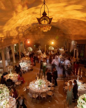An elegant wedding reception venue with amber lighting and crystal chandeliers.