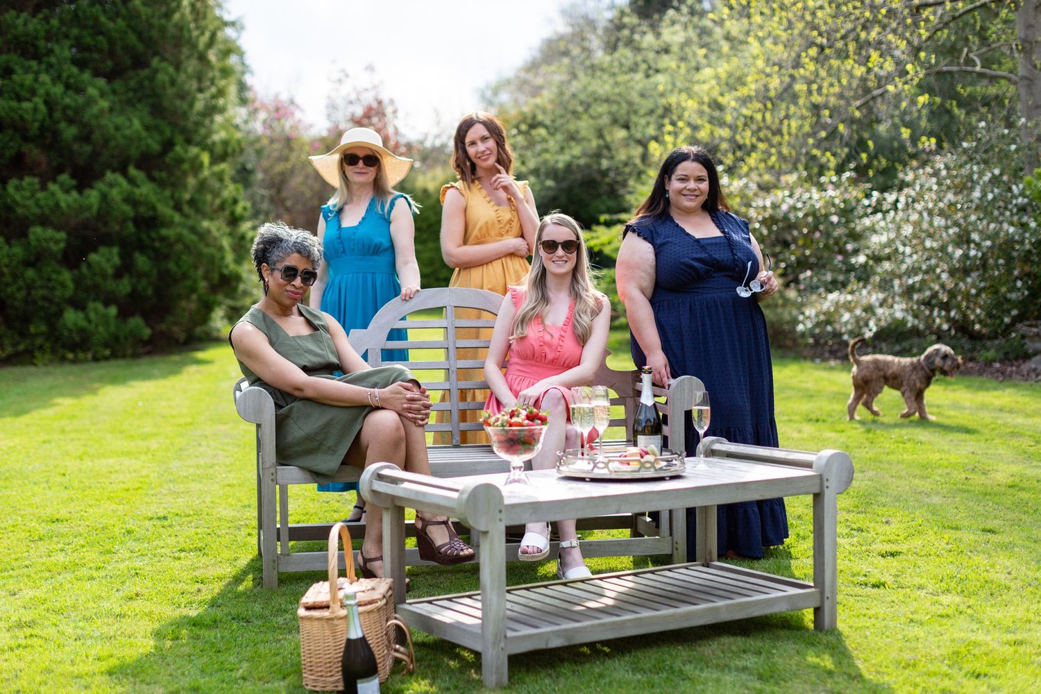 A group enjoys an outdoor garden party with drinks and snacks on a sunny day.