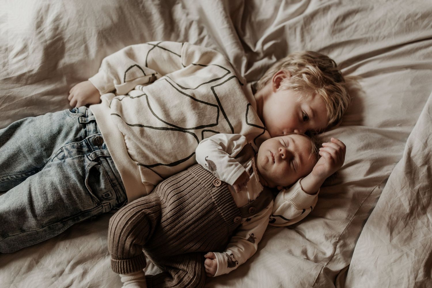 Broer geeft zijn kleine zusje en kus op haar hoofdje terwijl ze samen in bed liggen