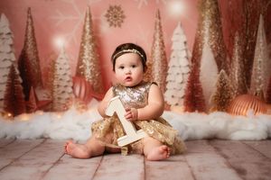 A festive holiday scene with pink and white decorations featuring glittering trees and sparkly ornaments in a winter wonderland setting.