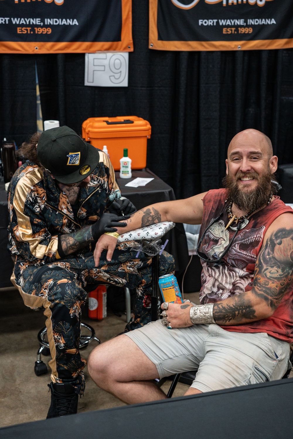 Smiling bearded man getting arm tattooed at Fort Wayne Indiana tattoo convention.