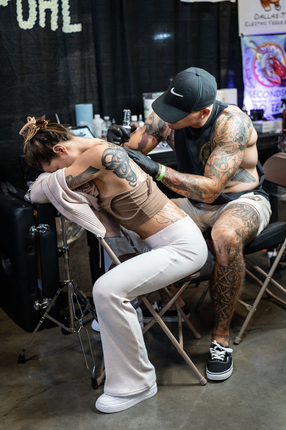 Tattoo artist applying detailed back tattoo on client at Dallas Electric Frequency convention.