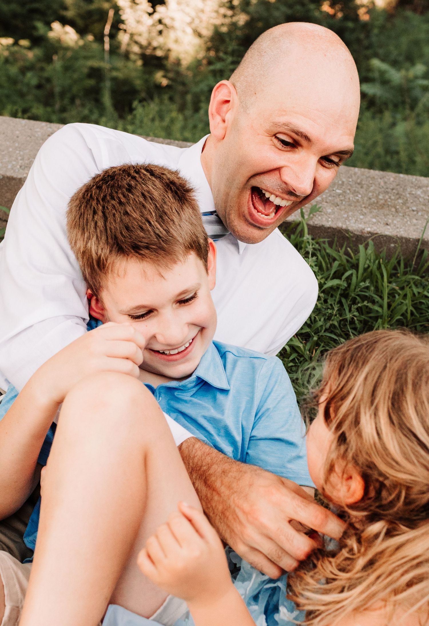 Laughing father and children playing together outdoors in a joyful candid moment.