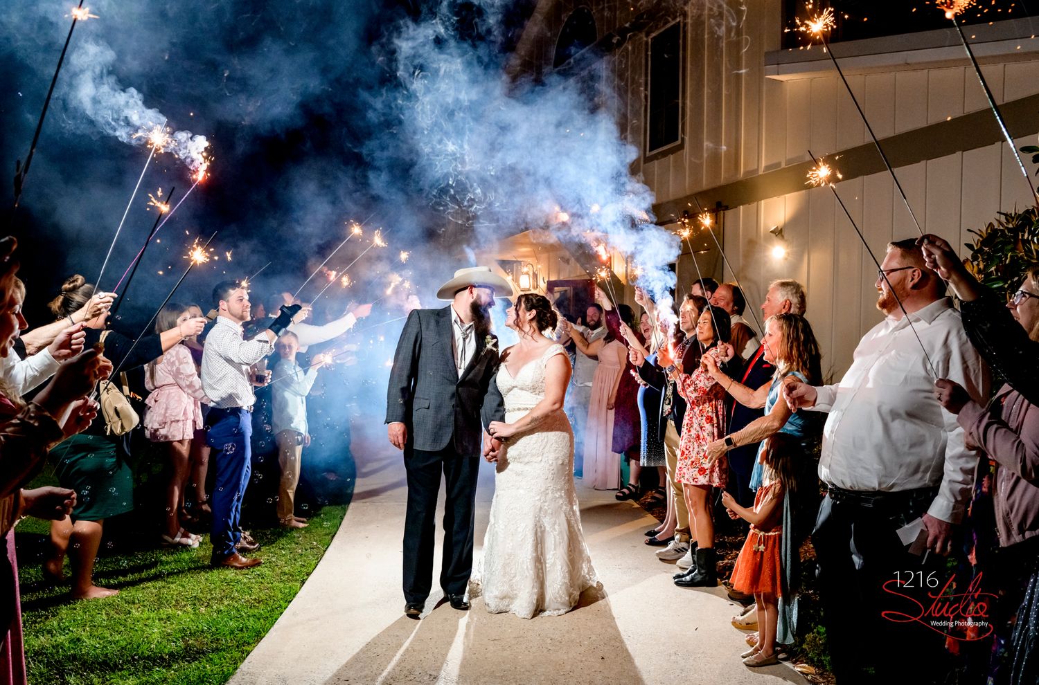 Nighttime sparkler send-off with guests lining pathway for newlyweds.