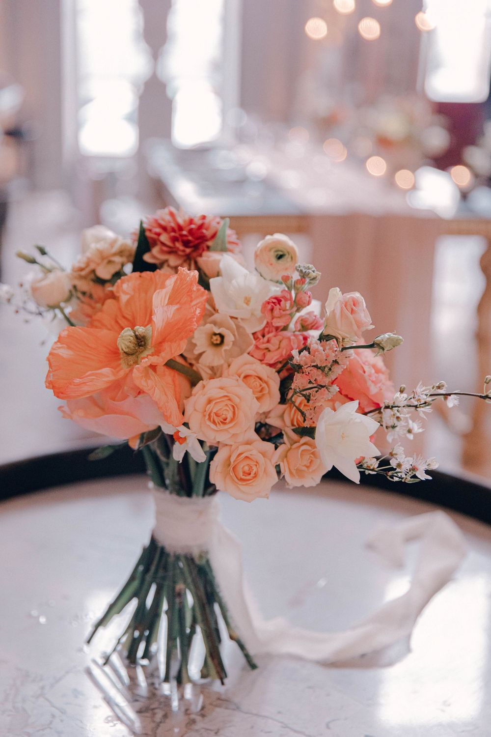 Elegant peach and coral floral centerpieces in glass vases on white tablecloths Ombersley court