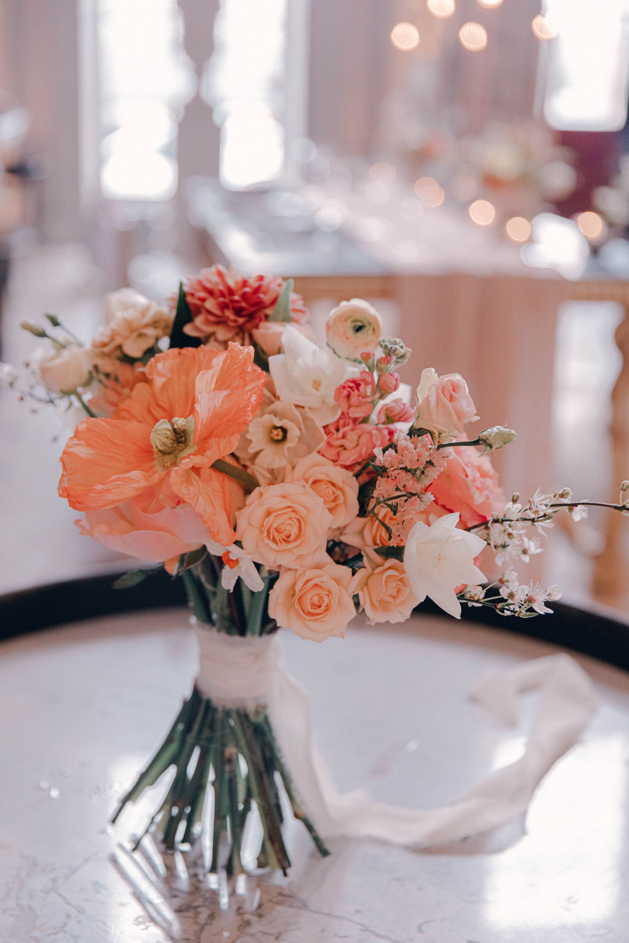Elegant peach and coral floral centerpieces in glass vases on white tablecloths Ombersley court