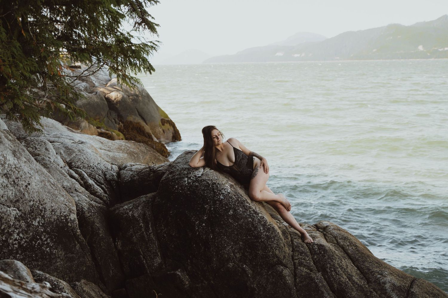 Couple relaxing on coastal rocks overlooking a dramatic seascape.