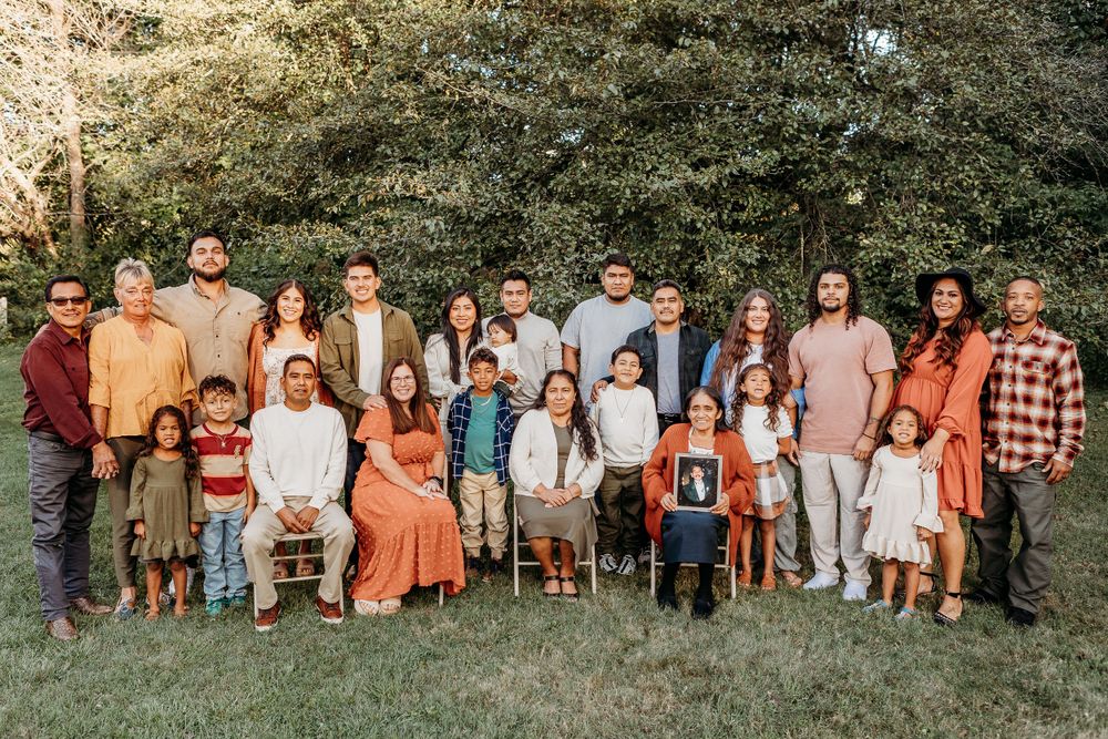 A large extended family poses together outdoors wearing coordinated fall colors for a group portrait.