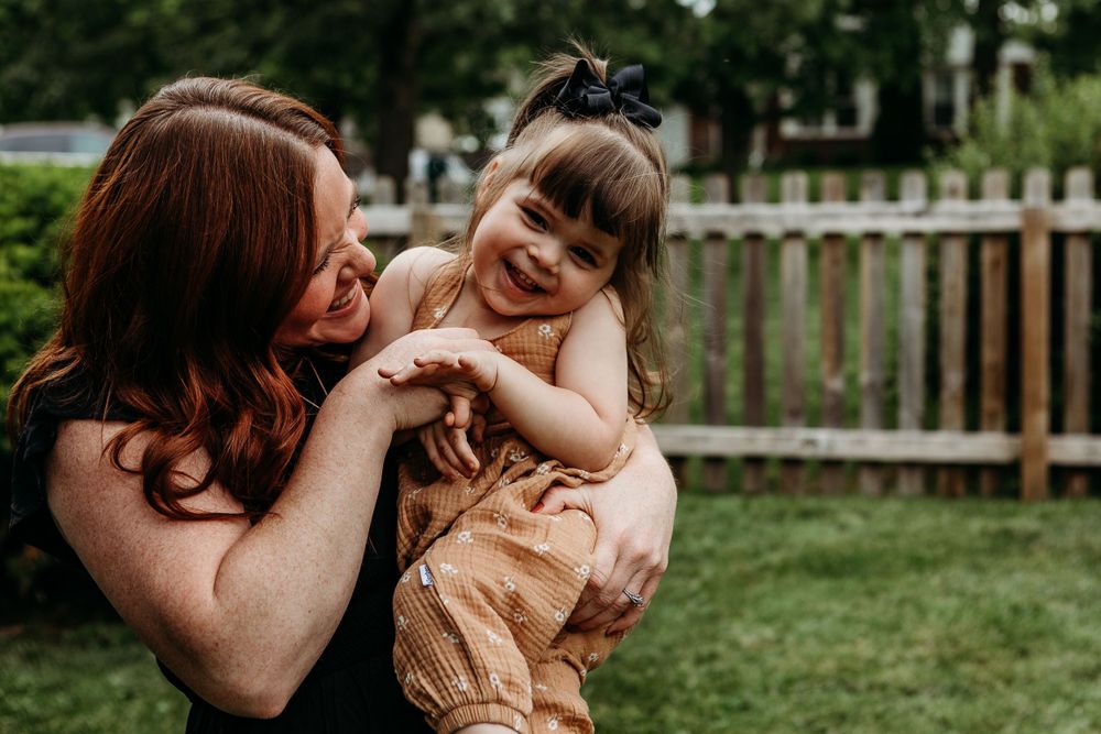 Sweet candid moment between parent and child outdoors in backyard setting.