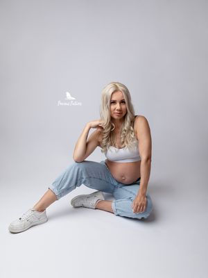 Casual studio maternity portrait with a blonde model in denim sitting on a white background, Precious Pictures photography, Malta.