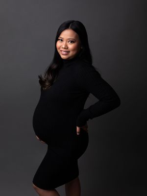 Classic studio maternity portrait in a black knit dress, showcasing the baby bump, by Precious Pictures photography, Malta